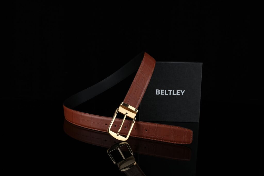 Stylish brown leather belt with a gold buckle displayed against a black background.