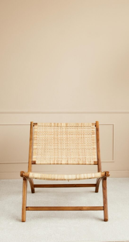 Elegant wicker chair with wooden frame against a neutral wall, perfect for interiors.
